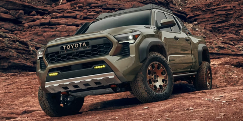 A 2026 Toyota Tacoma, showcasing its rugged off-road capabilities, parked on rocky terrain with a bold, aggressive front design and off-road tires.