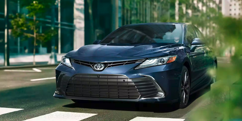 Blue Toyota Camry driving through city street